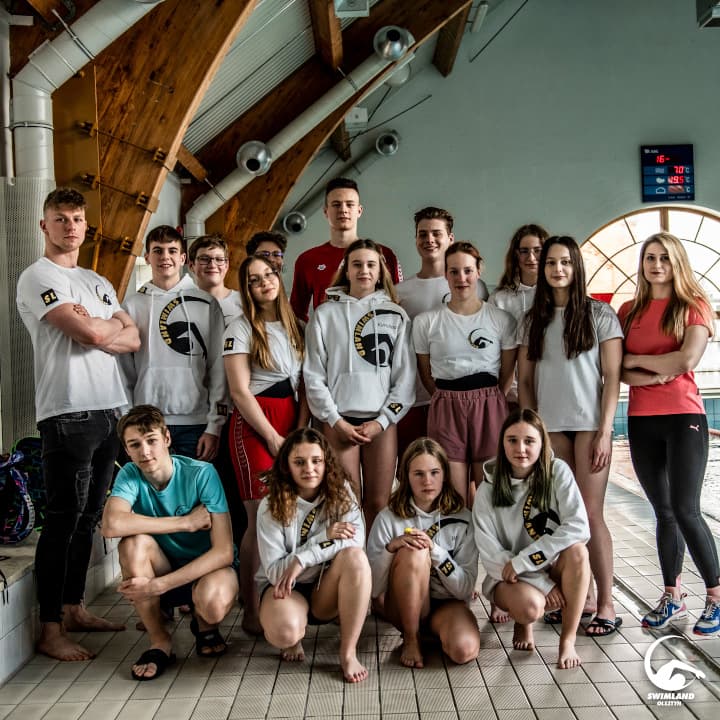 Zawodnicy Swimland Olsztyn w bluzach klubowych podczas wspólnego zdjęcia na hali basenowej
